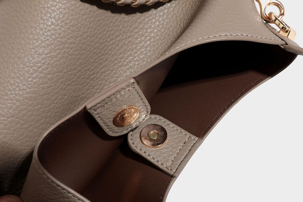 Schultertasche in genarbter Lederoptik im Hobo-Stil mit goldfarbener Kette, kurzem Tragegriff und dekorativem Anhänger an der Seite, Detailansicht