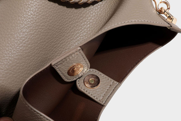 Schultertasche in genarbter Lederoptik im Hobo-Stil mit goldfarbener Kette, kurzem Tragegriff und dekorativem Anhänger an der Seite, Detailansicht