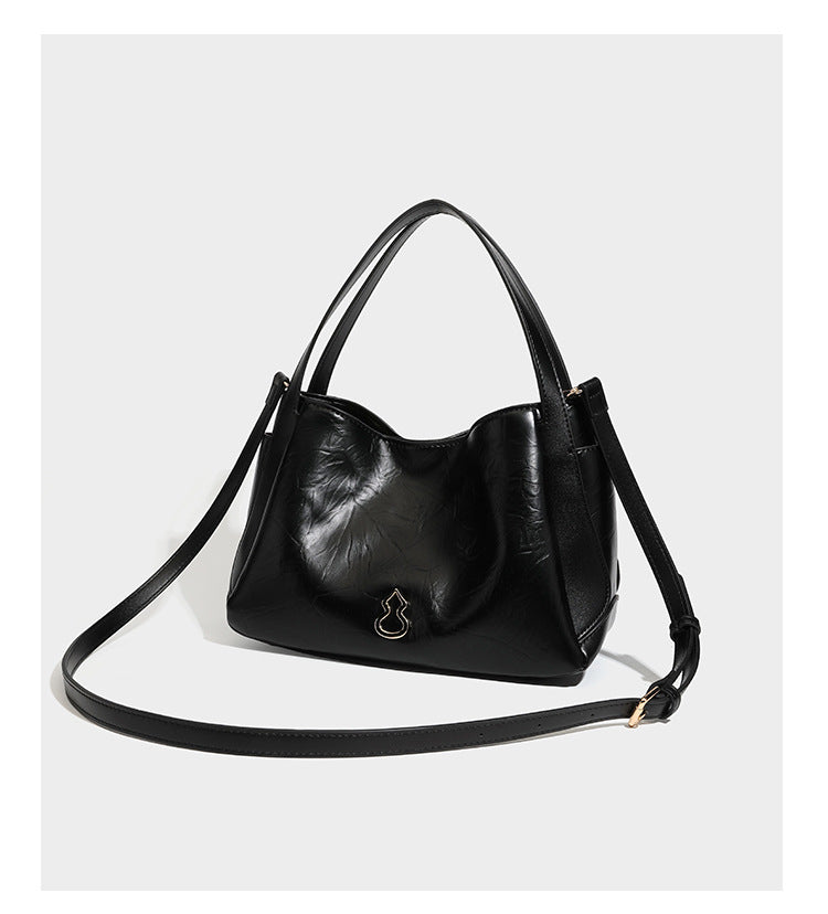 Black glossy crinkled leather-look convertible shoulder tote bag with gold gourd-shaped emblem hardware and detachable
