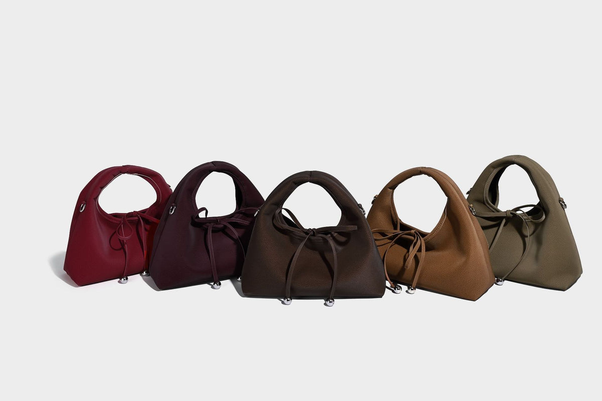 Pebbled matte trapezoid top-handle bag with drawstring bow closure, bead-tipped cords, silver-tone hardware, and detachable