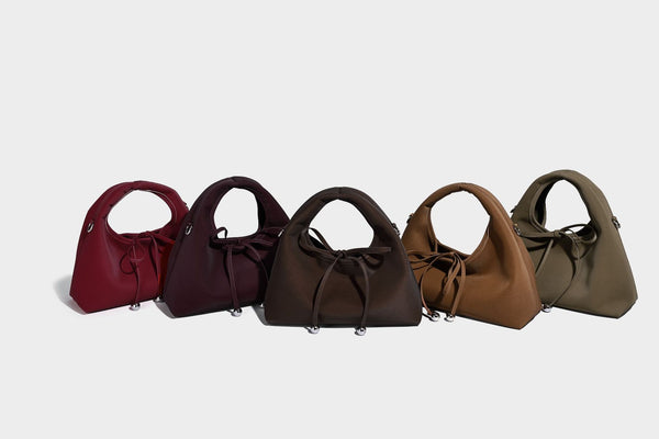 Pebbled matte trapezoid top-handle bag with drawstring bow closure, bead-tipped cords, silver-tone hardware, and detachable