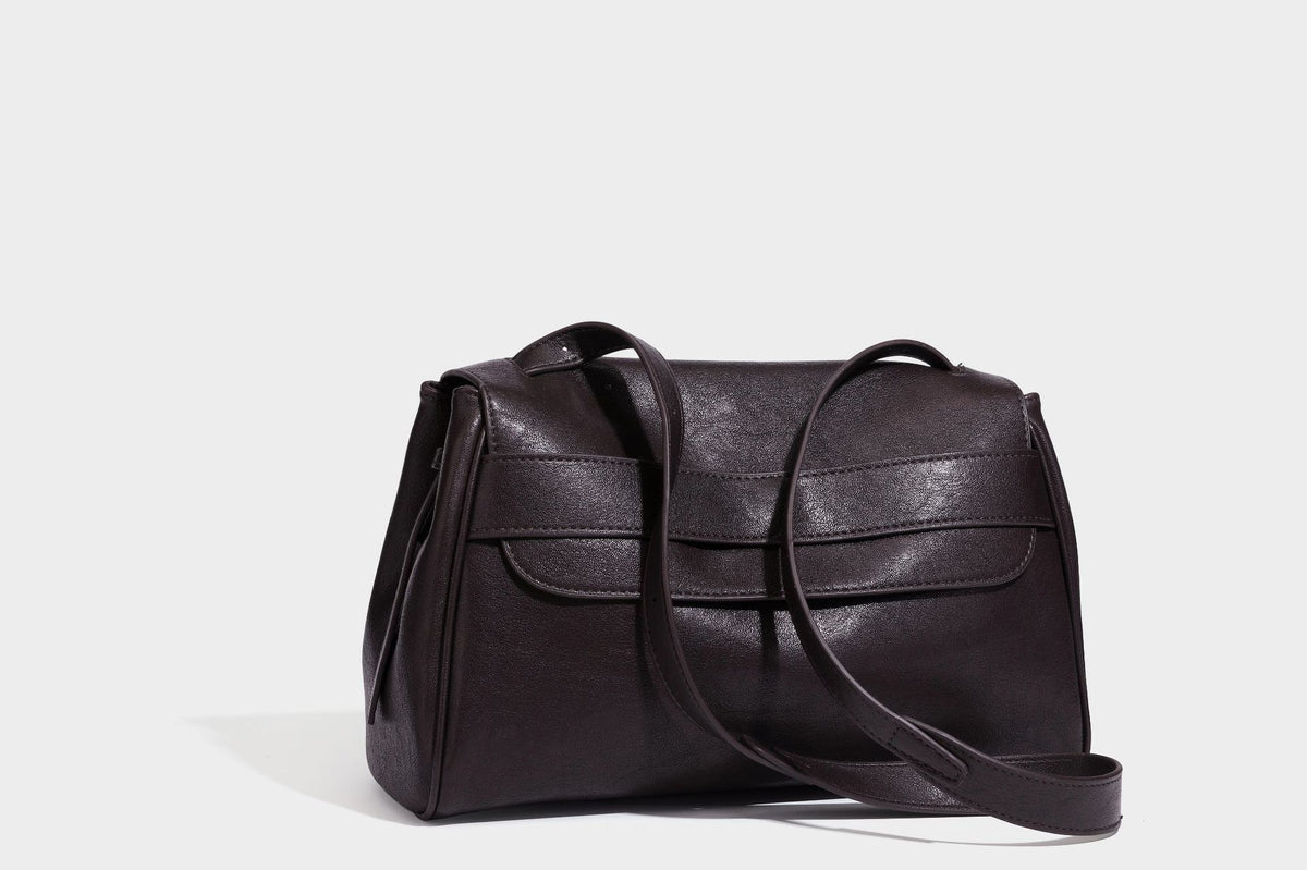 Strukturierte rechteckige dunkelbraune Schultertasche in Lederoptik mit Klappe, mehrlagigem Detail auf der Vorderseite und langem verstellbarem Riemen, Detailansicht
