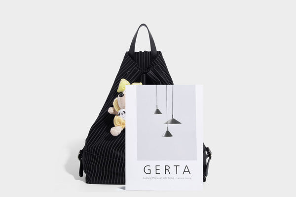 Schwarze wandelbare Rucksack-Handtasche mit Nadelstreifen, Kordelzugverschluss, Tragegriff aus Lederimitat und matten Metallbeschlägen, Detailansicht