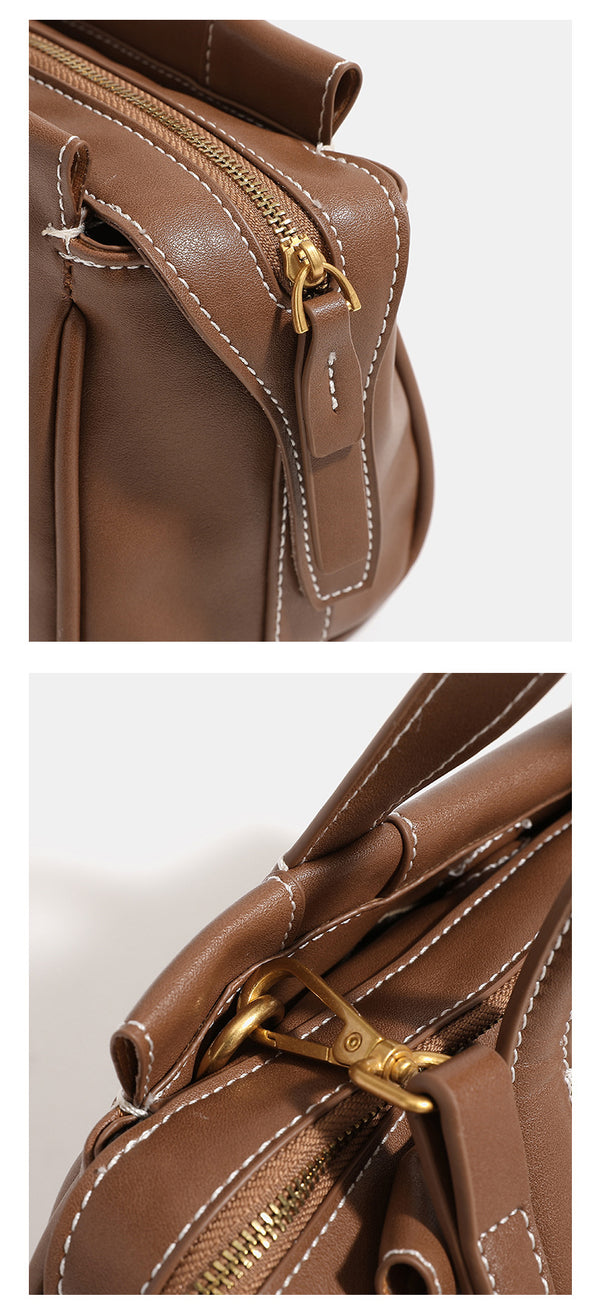 Compact structured satchel bag with dual top handles, gold-tone O-ring hardware, contrast topstitching, and detachable
