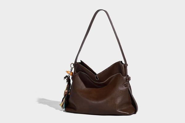 Large slouchy leather-look hobo tote bag with open top, adjustable shoulder strap, and colorful tassel bead charm, detail