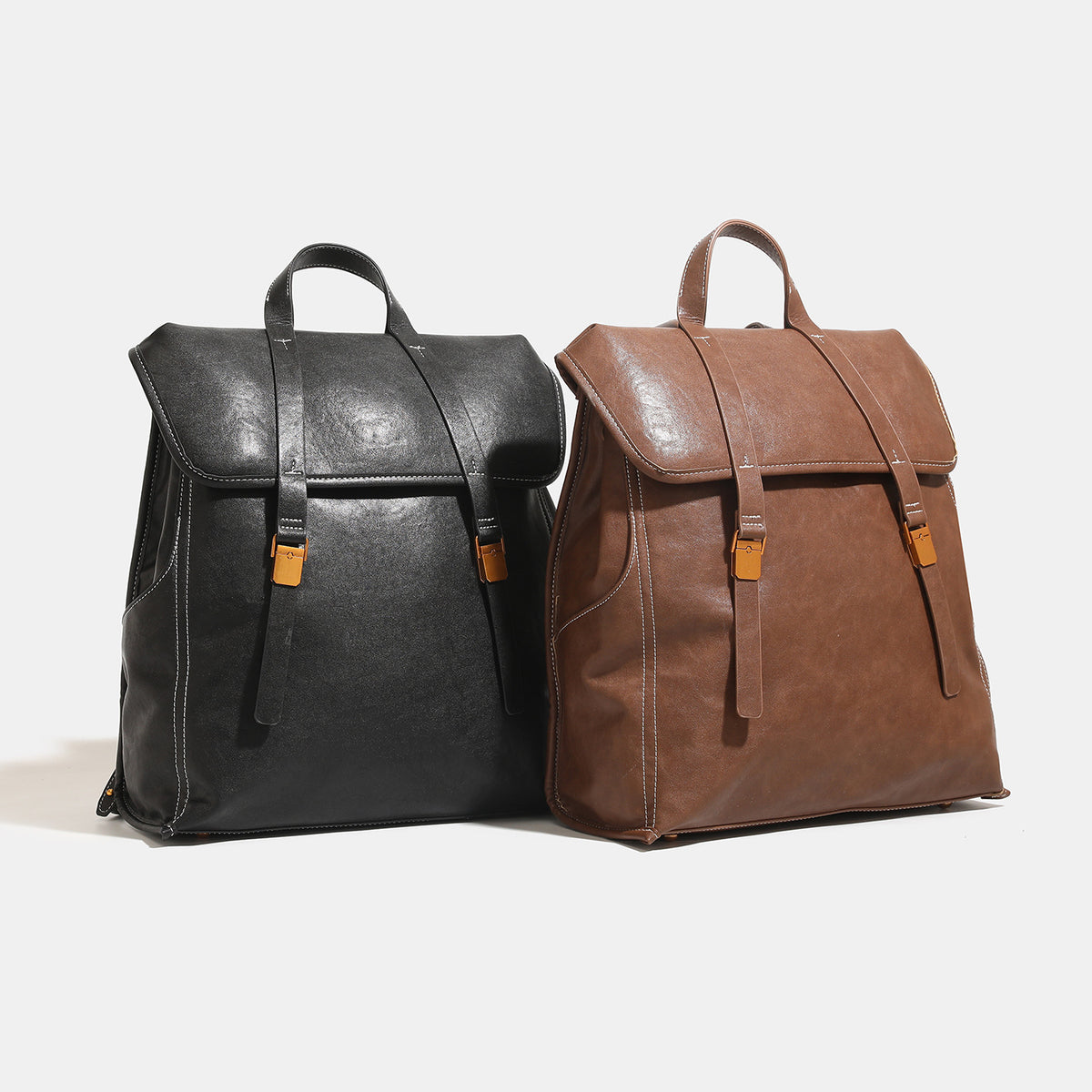 Structured leather-look flap backpack handbag with top handle, buckle front straps, white contrast stitching, and gold-tone