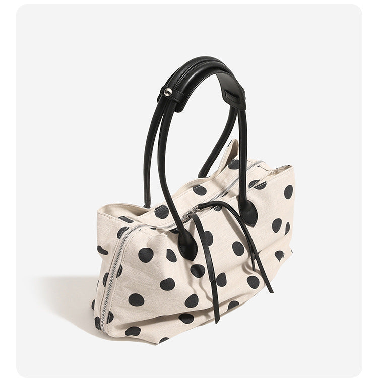 Cream canvas tote bag with black polka dots, rounded leather-look handles, and zip-top closure, detail view 8
