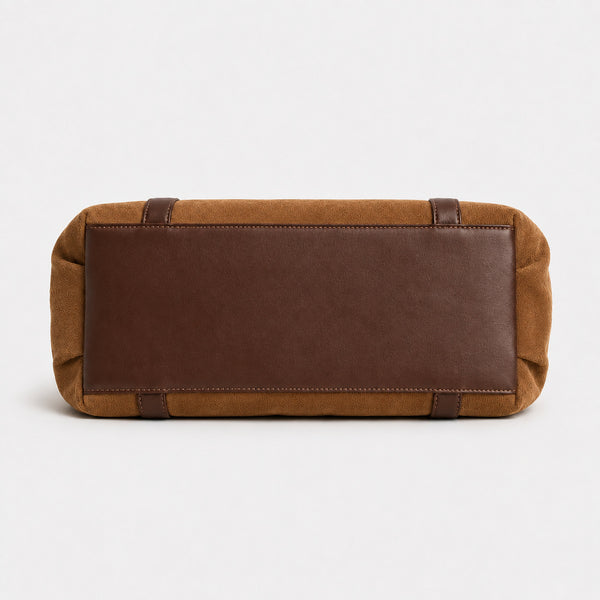 Soft suede-texture shoulder bag in brown with drawstring sides, leather-look vertical straps, gold-tone buckle hardware, and
