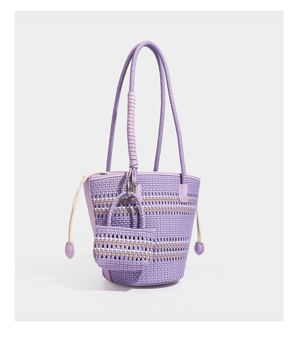 Light blue open-weave woven bucket tote bag with long braided shoulder straps, drawstring side ties, and attached mini pouch