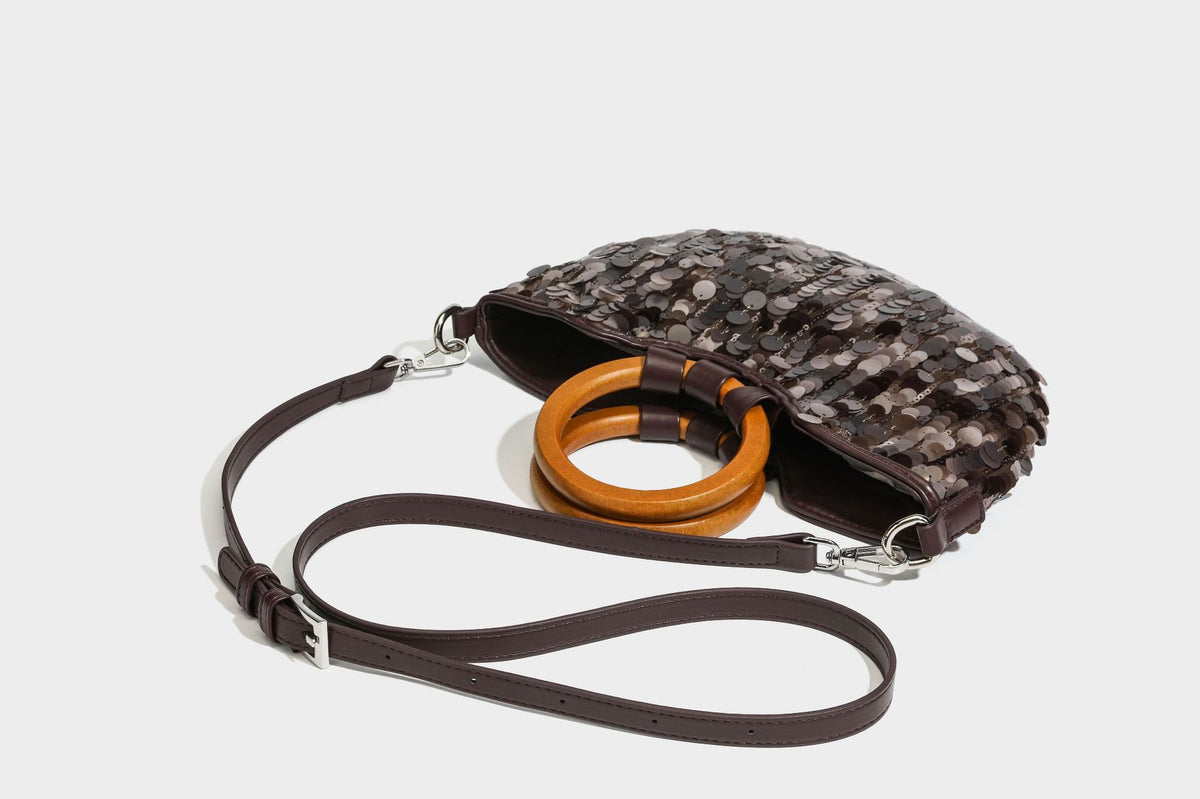 Small sequin half-moon handbag with circular wood-look ring handles and detachable leather-look shoulder strap, detail view