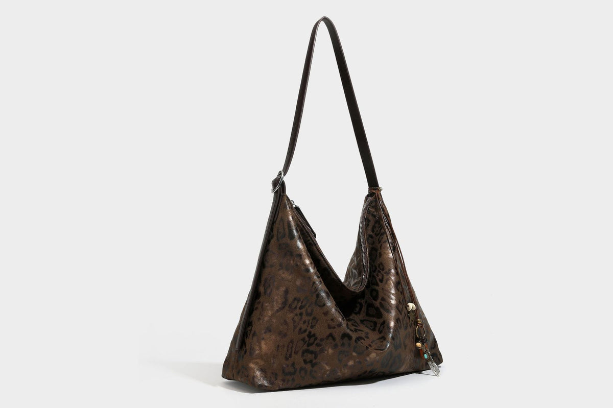 Slouchy leopard print hobo shoulder bag with glossy coated finish, top zipper closure, dark brown trim, and dangling charm
