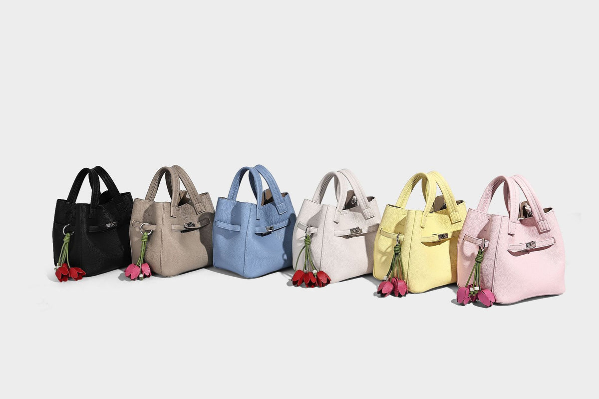 Small structured pebbled bucket tote bag with dual top handles, silver turn-lock front pocket, and detachable shoulder strap