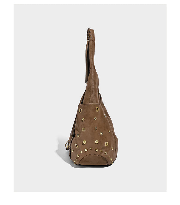 Slouchy crescent hobo bag in matte brown suede-like finish with gold-tone studs, grommets, braided top handle, tassel side