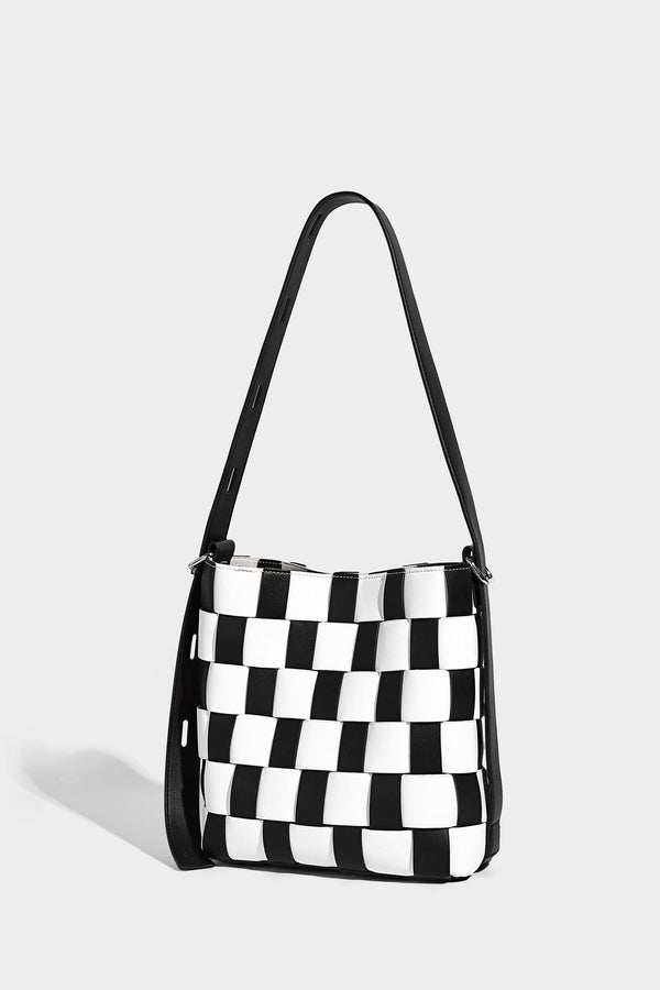 Hand-woven black-and-white checkerboard bucket bag with smooth black trim, silver-tone ring hardware, and adjustable