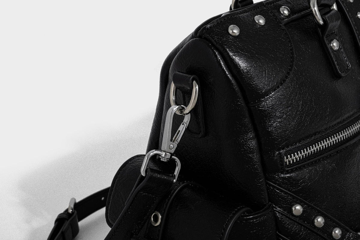 Schwarze, glänzende Henkeltasche mit genarbter Struktur, silberfarbenen Nieten, Riemendetail mit Schnalle, zwei Henkeln und breitem, mit Nieten besetztem Schulterriemen