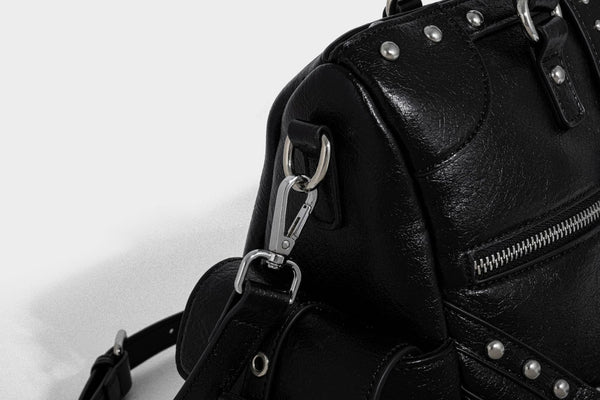 Schwarze, glänzende Henkeltasche mit genarbter Struktur, silberfarbenen Nieten, Riemendetail mit Schnalle, zwei Henkeln und breitem, mit Nieten besetztem Schulterriemen