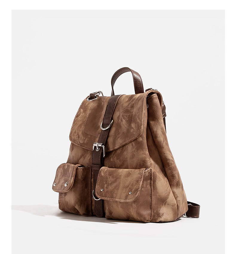 Compact distressed leather-look tan-brown backpack handbag with flap-and-buckle closure, two front patch pockets, top handle
