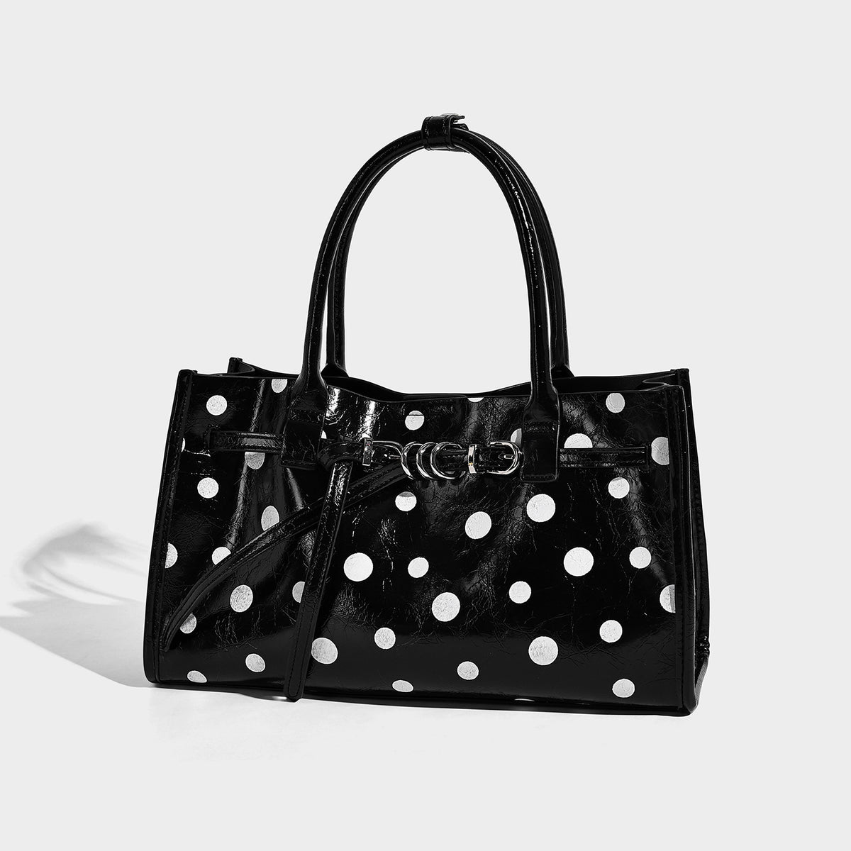 Structured glossy leather-look polka-dot satchel tote with dual top handles and detachable shoulder strap, front view