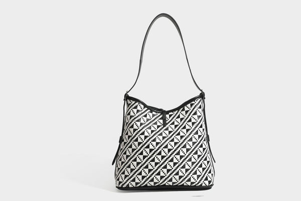 Woven geometric bucket shoulder bag in white and dark brown two-tone pattern with leather-look trim and drawstring top
