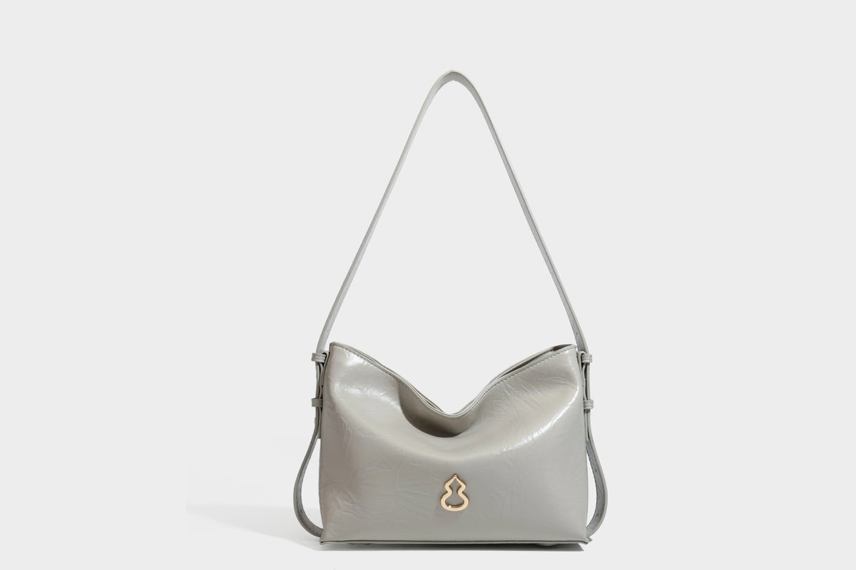 Lässig fallende Hobo-Schultertasche mit offenem Oberteil aus glänzender, karamellbrauner Lederoptik, mit Logo-Beschlägen in Goldoptik und langem, verstellbarem