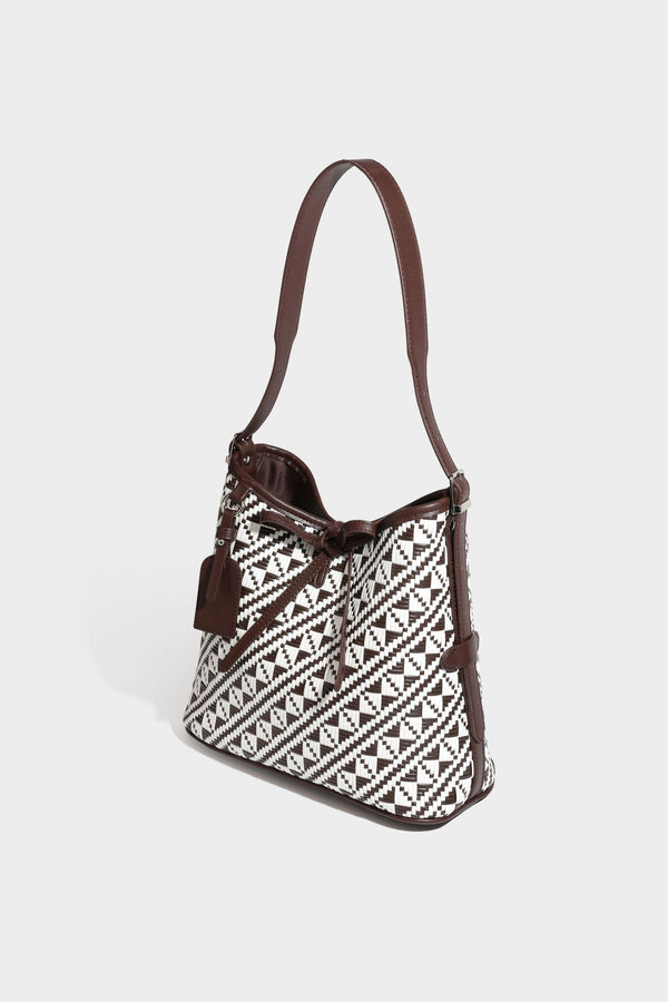Woven geometric bucket shoulder bag in white and dark brown two-tone pattern with leather-look trim and drawstring top