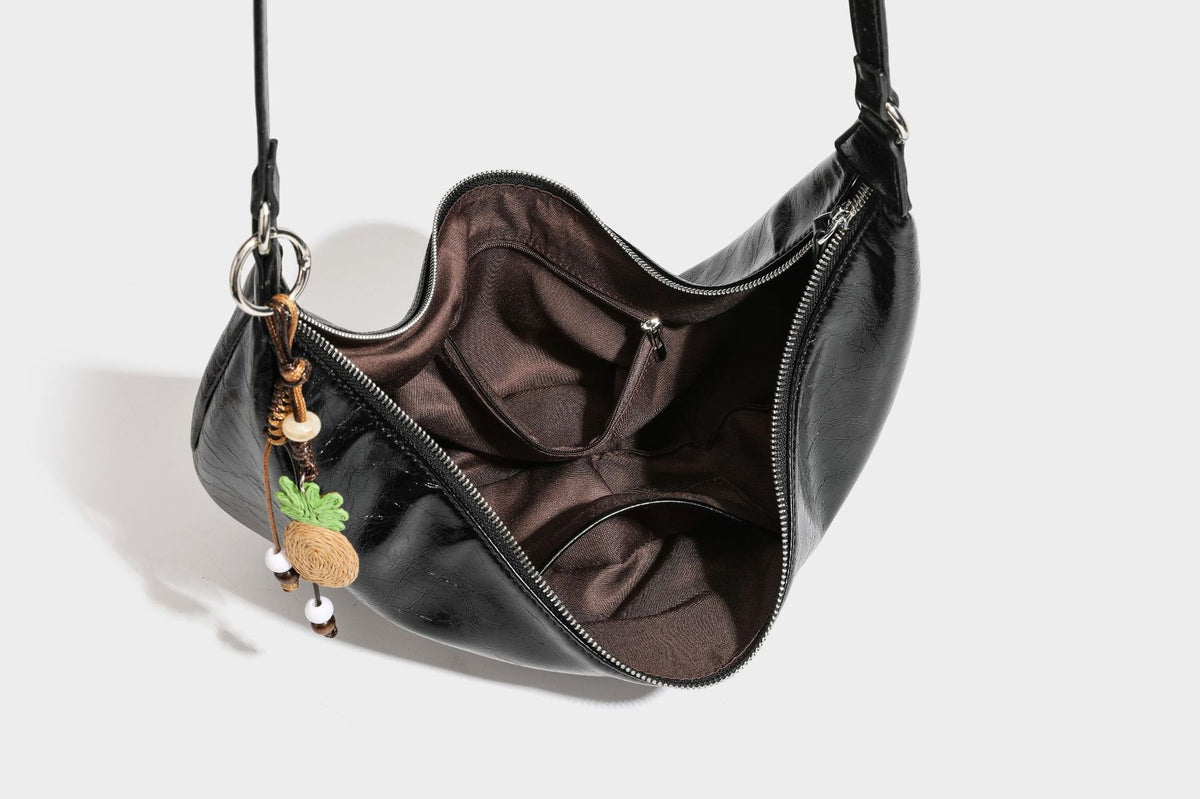 Legere, halbmondförmige Hobo-Schultertasche in glänzender, geknautschter Lederoptik mit schmalem Riemen, Ringbeschlägen in Silberoptik und