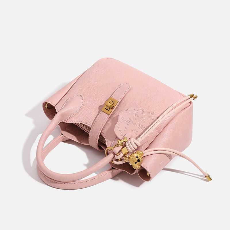 Small structured pebbled leather-look mini tote bag with gold-tone hardware, front toggle closure, knotted bear tassel charm