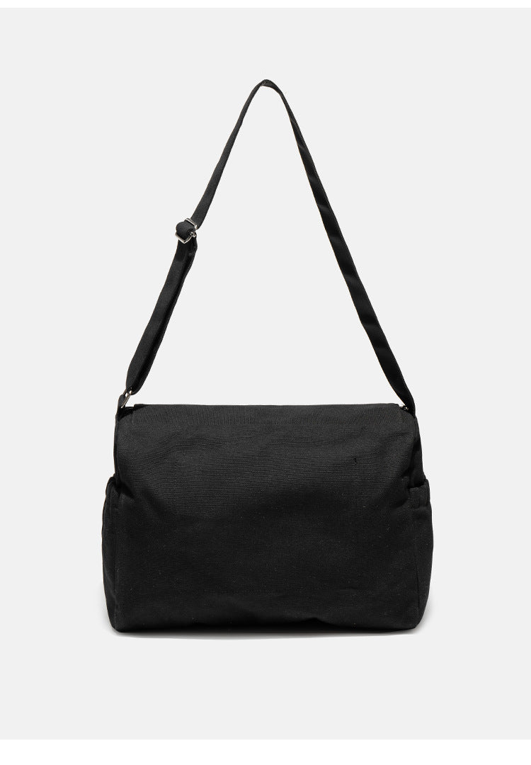 Große schwarze Messenger-Tasche aus mattem Canvas mit Überschlag vorn, Reißverschluss oben, elastischen Seitentaschen und verstellbarem silberfarbenem