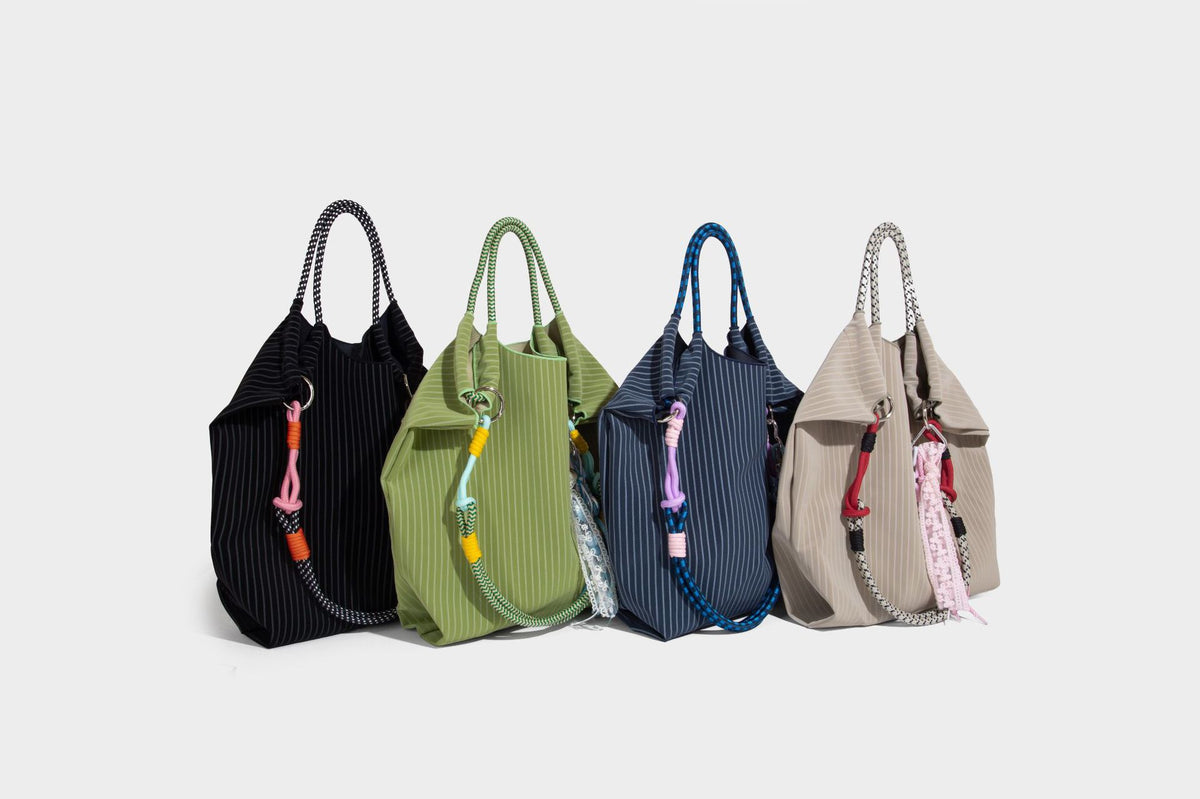 Slouchy pinstripe tote bag with braided rope handles, metal ring hardware, and colorful knotted rope charm, detail view 38