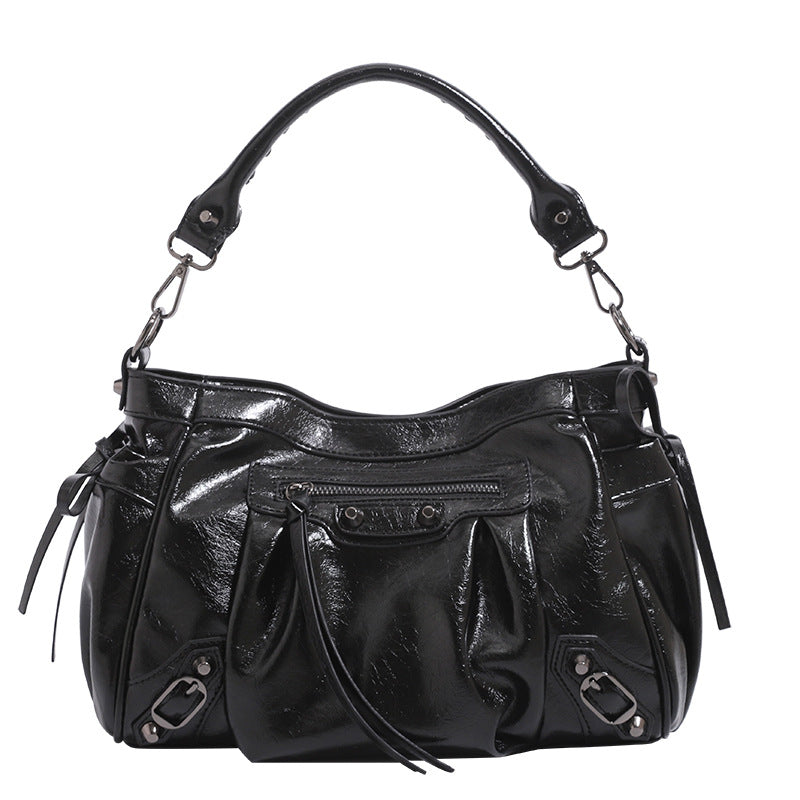 Slouchy glossy crinkle leather-look shoulder bag with silver stud accents, tassel ties, front zip pocket, and top handle