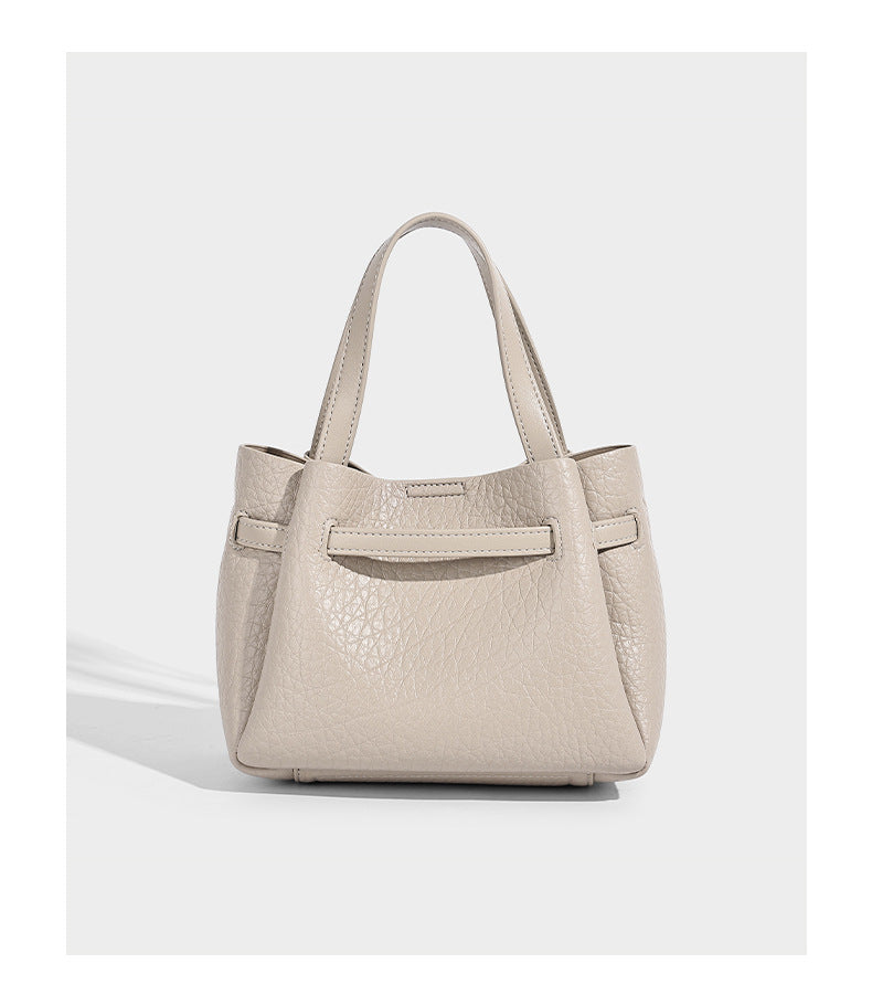 Small structured pebbled bucket tote with double top handles, silver turn-lock hardware, and detachable shoulder strap