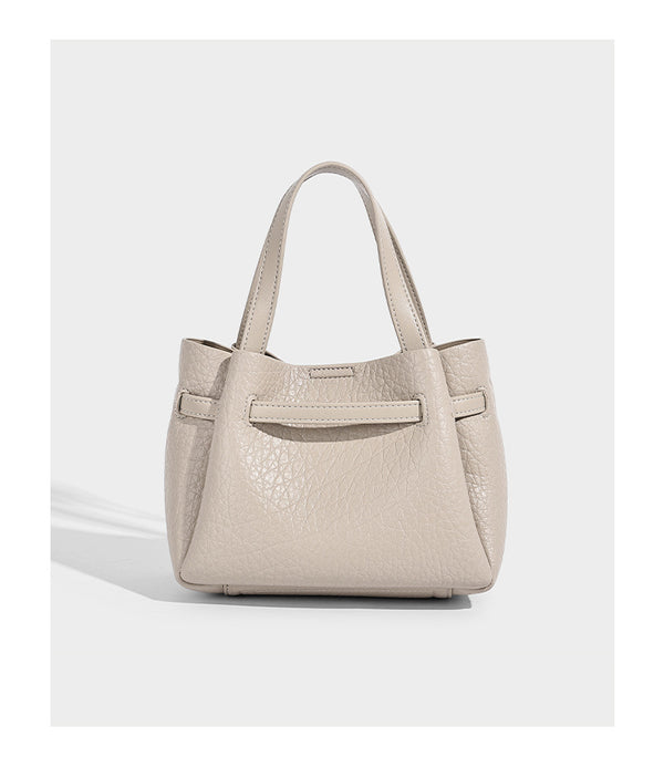 Small structured pebbled bucket tote with double top handles, silver turn-lock hardware, and detachable shoulder strap