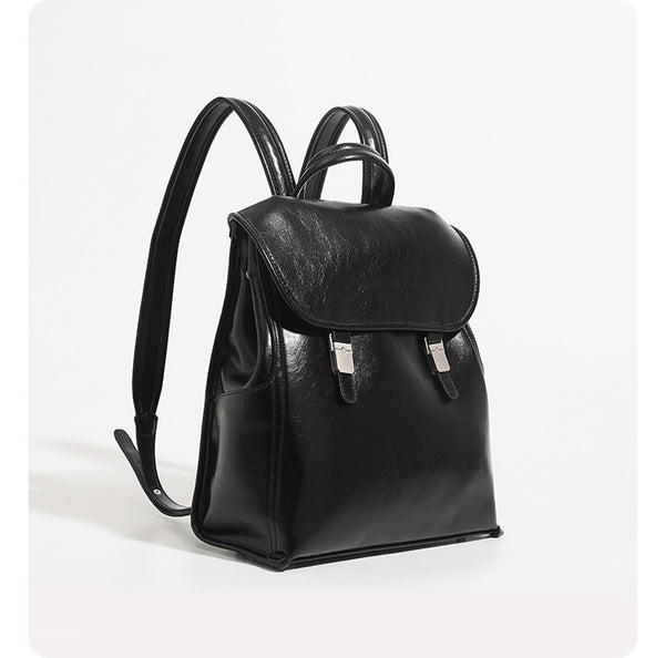 Structured glossy leather-look flap backpack handbag with dual buckle closures, top handle, and silver-tone hardware, detail