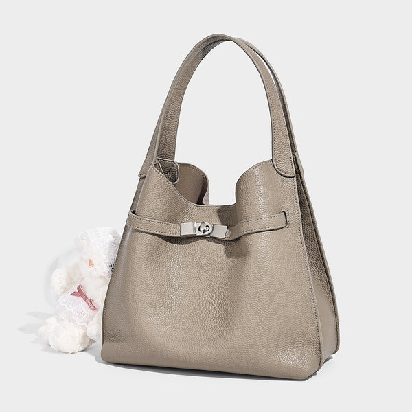 Geräumige Tote-Bag in genarbter Lederoptik mit Riemendetail und Drehverschluss in Silberoptik sowie zwei Henkeln, Vorderansicht