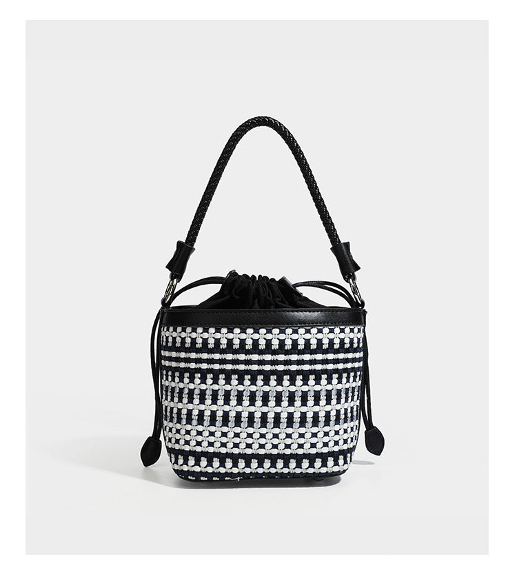 Small structured woven checker bucket bag with braided top handle, drawstring closure, and silver-tone hardware in black