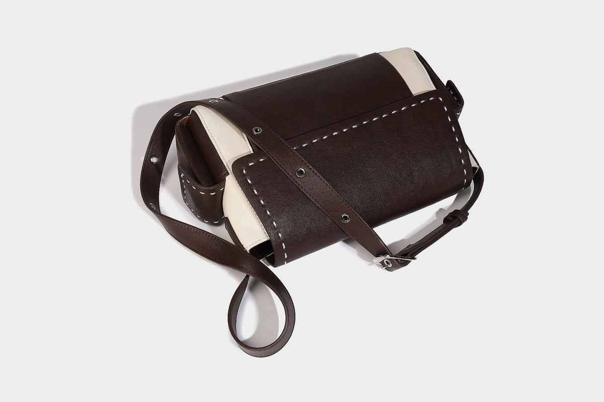 Structured flap crossbody bag in dark brown and cream color-block with white contrast stitching, adjustable shoulder strap