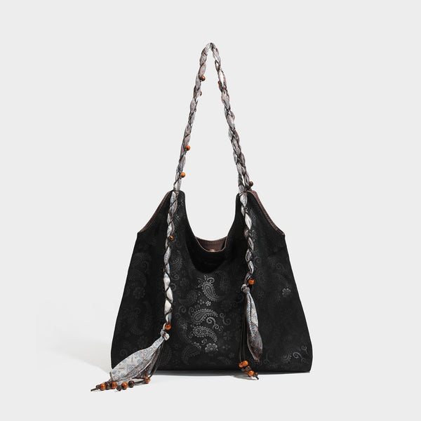 Slouchy paisley-embossed suede-look shoulder tote bag with braided patterned fabric straps and wood bead accents, detail view