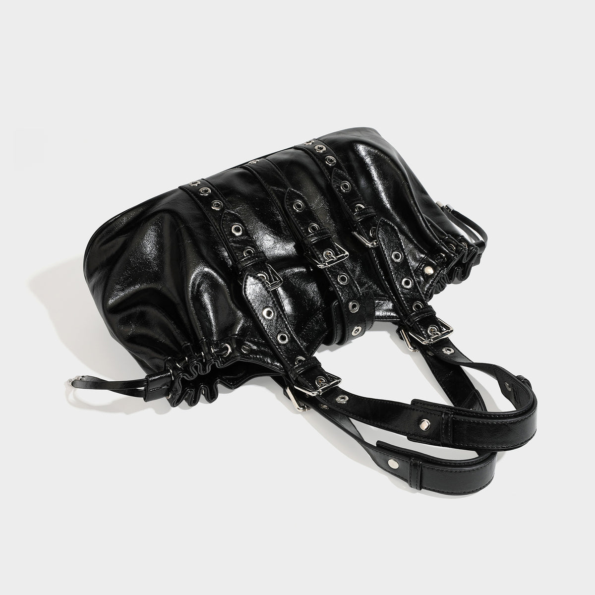 Large black glossy leather-look tote bag with silver buckle straps, eyelet grommet panels, drawstring side gathers, and