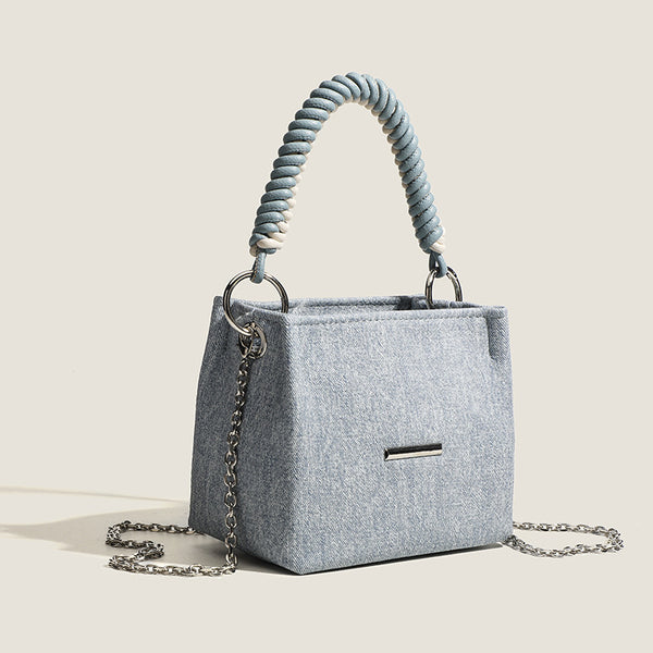 Small structured trapezoid mini bag with coiled rope top handle and silver-tone chain strap in textured fabric, detail view 3