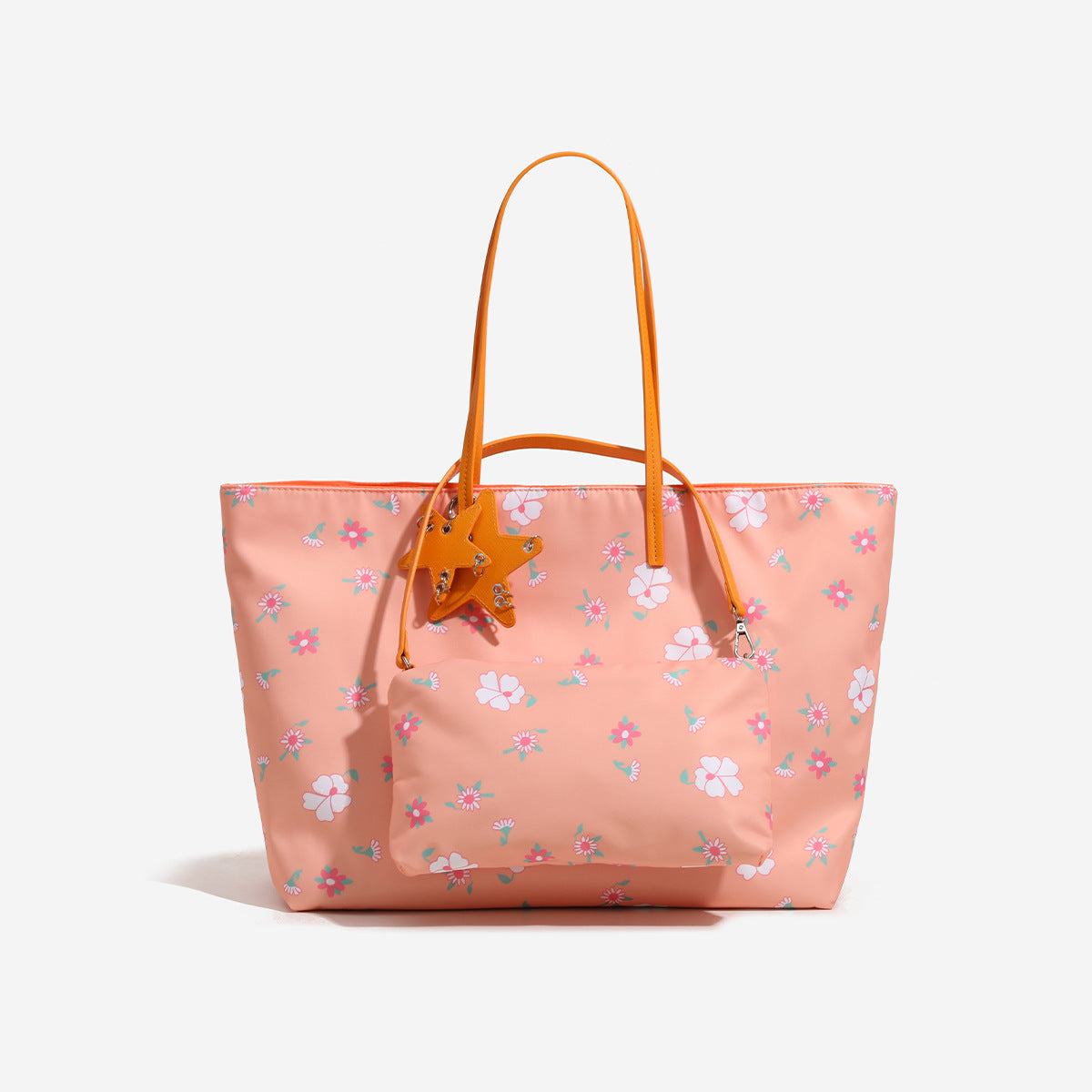 Large reversible floral print tote bag with slim shoulder straps, star charm hardware, and matching zip pouch, detail view 6