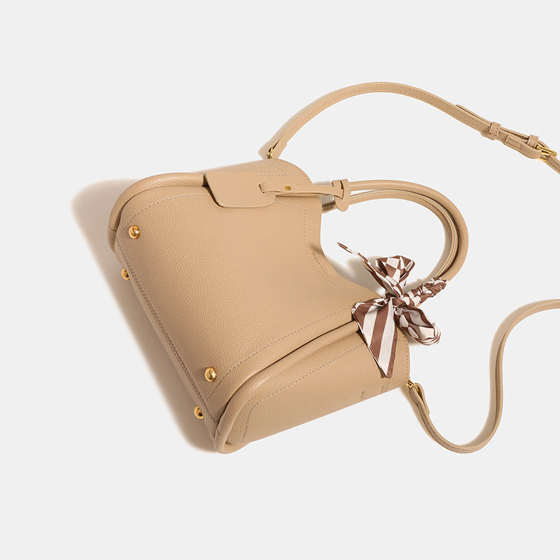Structured pebbled tote bucket bag in apricot with braided top handle, checkered bow scarf, gold-tone hardware, and, detail
