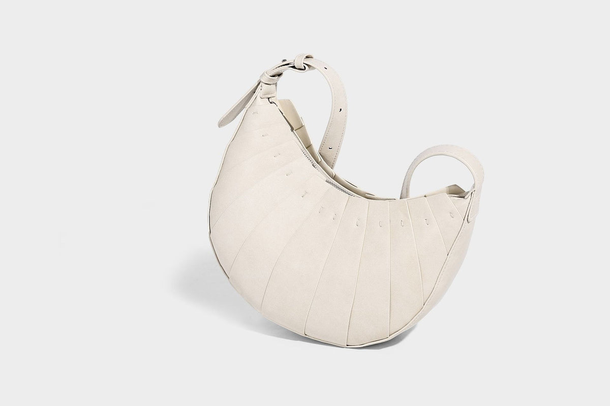 Crescent half-moon shoulder bag with vertical panel seaming, matte-satin leather-look finish, and adjustable gold-tone