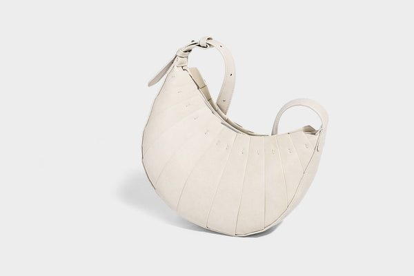 Crescent half-moon shoulder bag with vertical panel seaming, matte-satin leather-look finish, and adjustable gold-tone