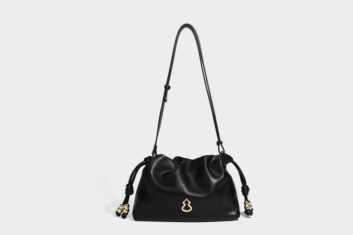 Slouchy ruched drawstring shoulder bag in smooth leather-look finish with gold-tone emblem and slim adjustable strap, detail