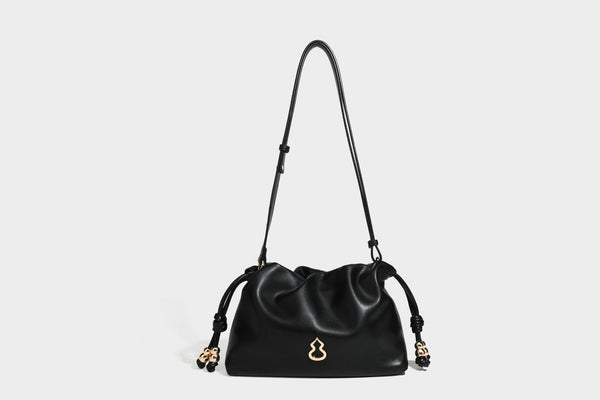 Slouchy ruched drawstring shoulder bag in smooth leather-look finish with gold-tone emblem and slim adjustable strap, detail