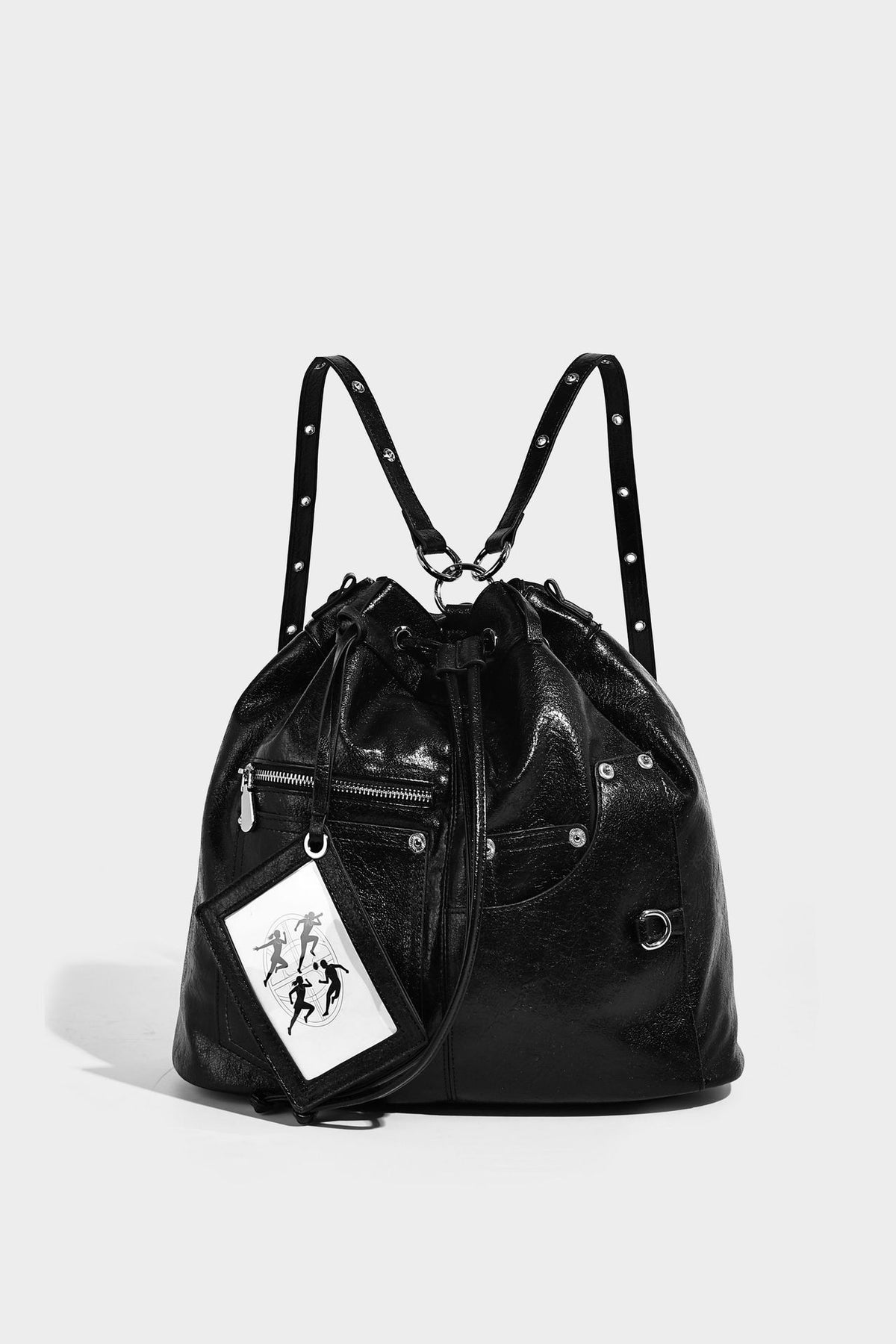 Glossy black convertible bucket backpack with silver grommet-studded straps, drawstring cinch closure, and front zip pocket