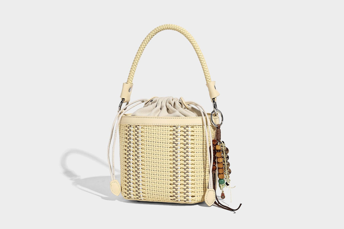 Small woven bucket bag with drawstring top, braided handle, detachable crossbody strap, and silver-tone ring hardware, detail