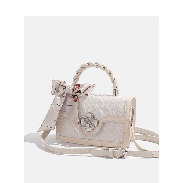 Ivory structured mini crossbody bag with crinkled leather-look finish, silk scarf top handle, silver four-petal flower clasp