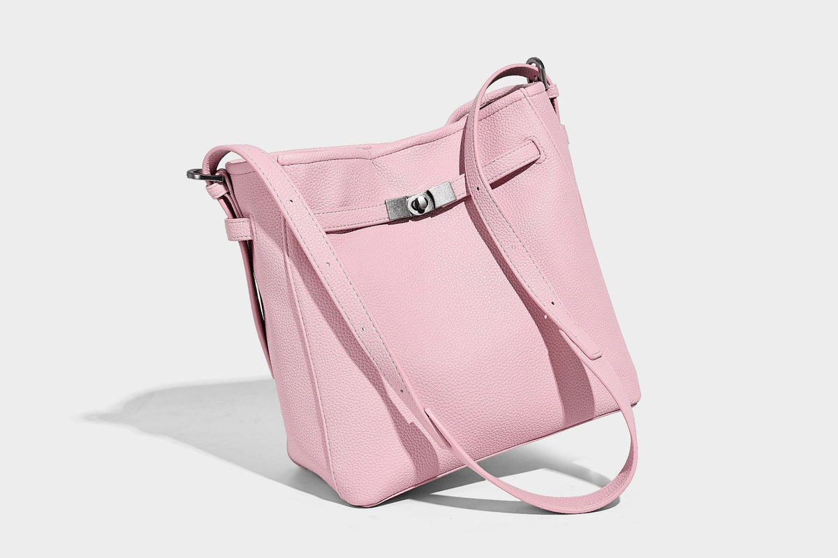 Soft-structured pebbled bucket shoulder bag with front turn-lock strap detail, adjustable strap, and hanging floral tassel