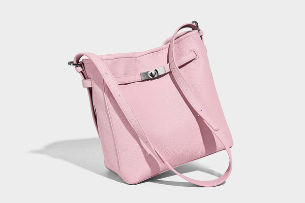 Soft-structured pebbled bucket shoulder bag with front turn-lock strap detail, adjustable strap, and hanging floral tassel